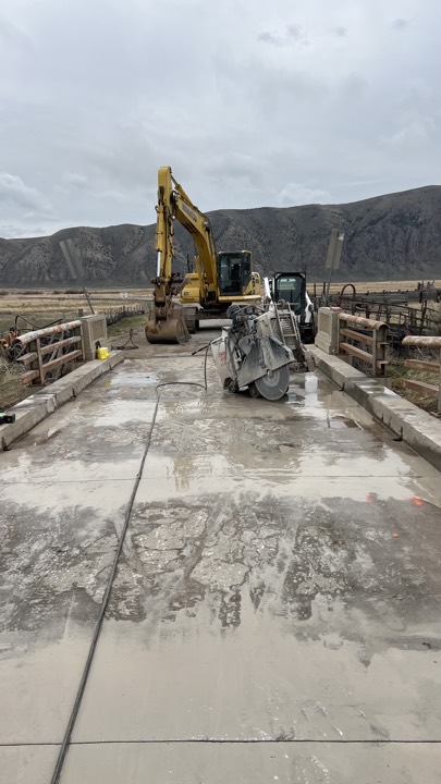 Slab sawing a concrete deck with an excavator standing by